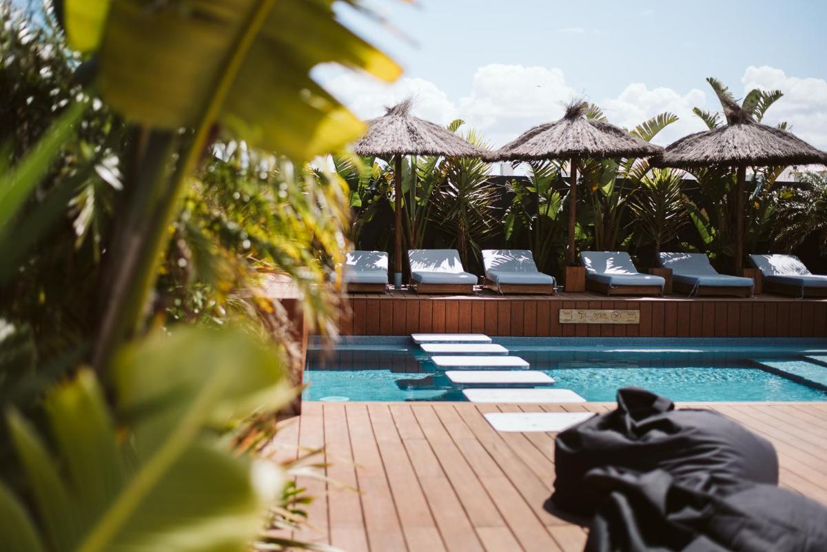 uma piscina com cadeiras e guarda-sóis num resort em The Salty Pelican Yoga & Surf Retreat em Peniche