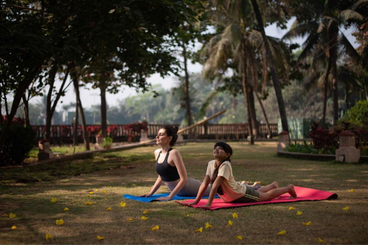 two women sitting on mats in a park at The Westin Mumbai Powai Lake in Mumbai