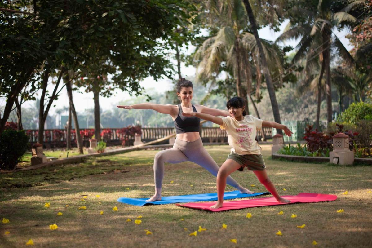 a woman and a child are standing on surfboards at The Westin Mumbai Powai Lake in Mumbai