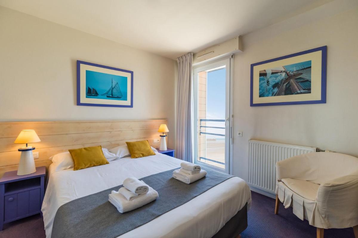 une chambre avec un lit, une chaise et une fenêtre dans l'établissement Hôtel Miléade de la Plage - Binic, à Binic