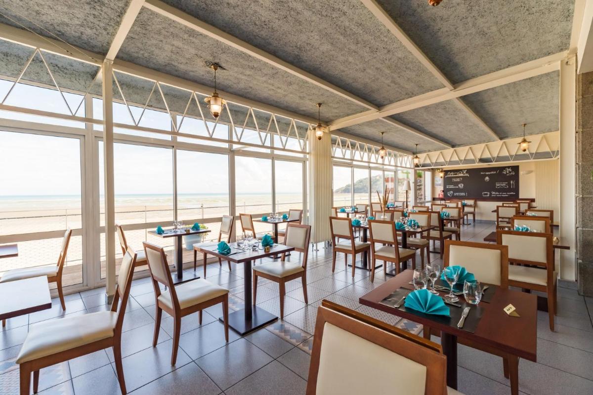 un restaurant avec des tables et des chaises et une vue sur l'océan dans l'établissement Hôtel Miléade de la Plage - Binic, à Binic 29 autres photos