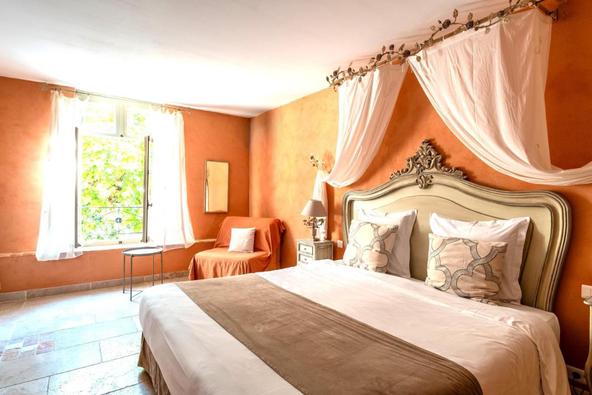 une chambre avec un grand lit et une fenêtre dans l'établissement Hôtel Le Mas des Grès & Restaurant Sous les Platanes, à Lagnes