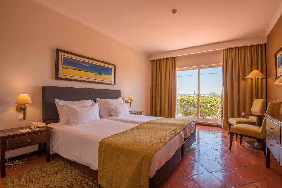 um quarto de hotel com uma cama grande e uma janela em Vila Gale Alentejo Vineyard - Clube de Campo em Albernoa