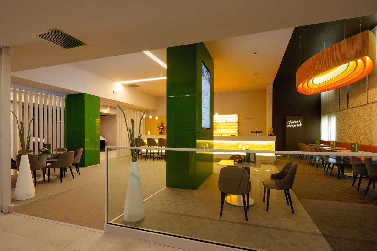 un hall avec une table et des chaises dans un bâtiment dans l'établissement Hotel Plaza - site du Futuroscope, à Chasseneuil-du-Poitou