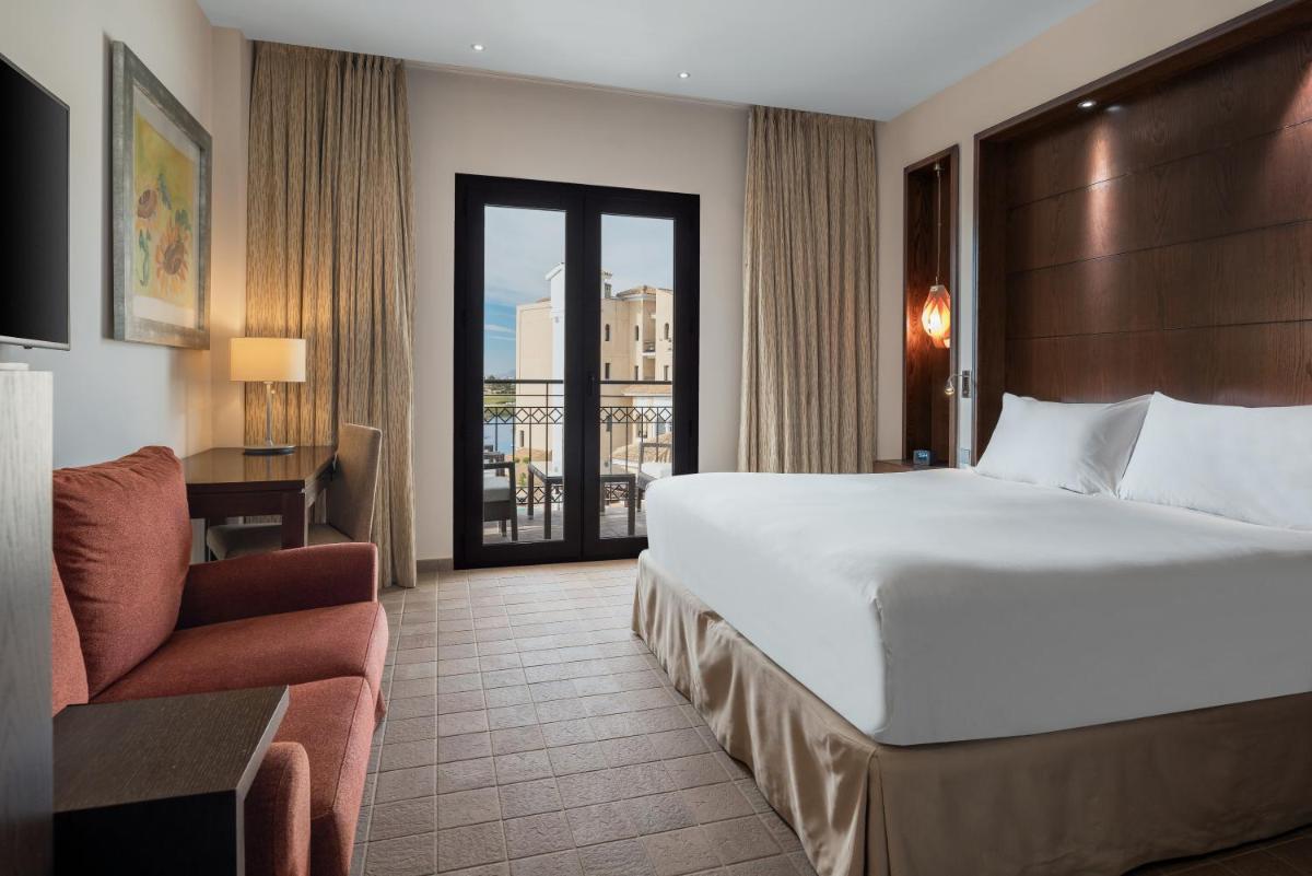 Una habitación de hotel con una cama grande y una silla. en Doubletree By Hilton La Torre Golf Resort, en Roldán
