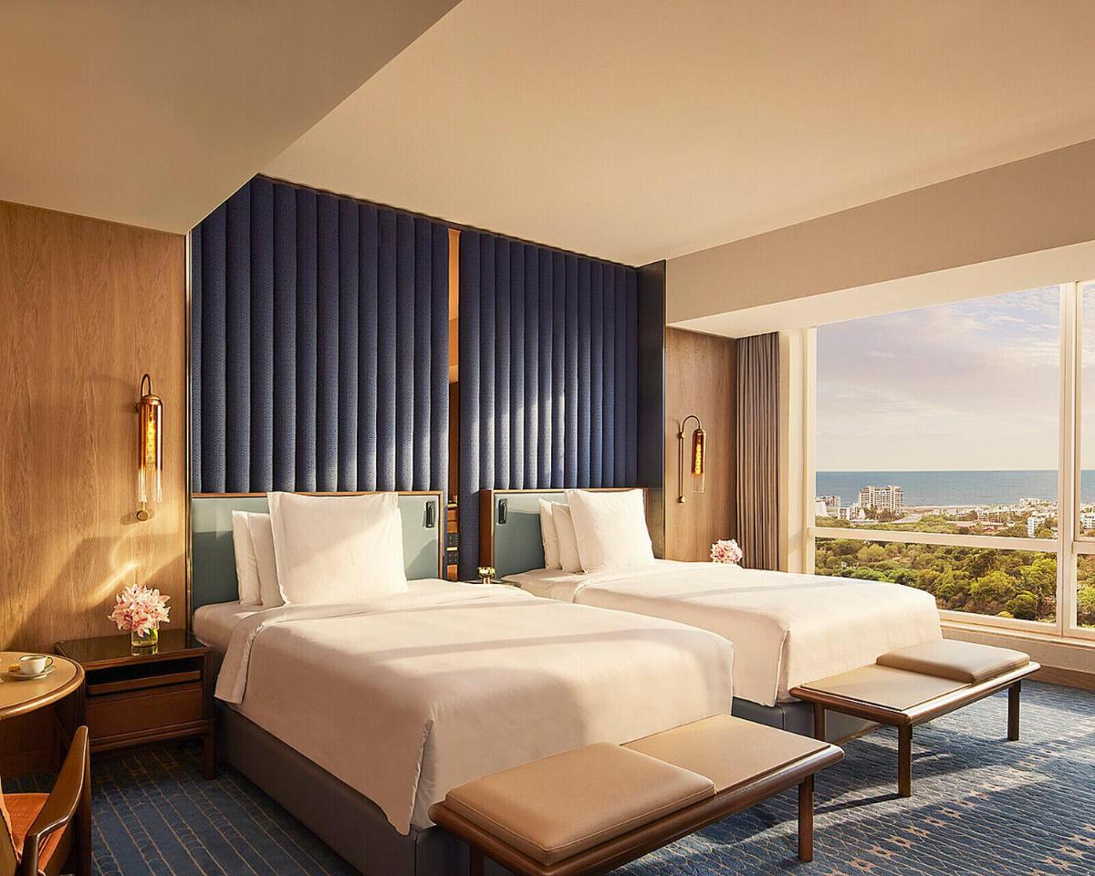 a hotel room with two beds and a large window at Four Seasons Hotel Mumbai in Mumbai a hotel room with two beds and a large window at Four Seasons Hotel Mumbai in Mumbai