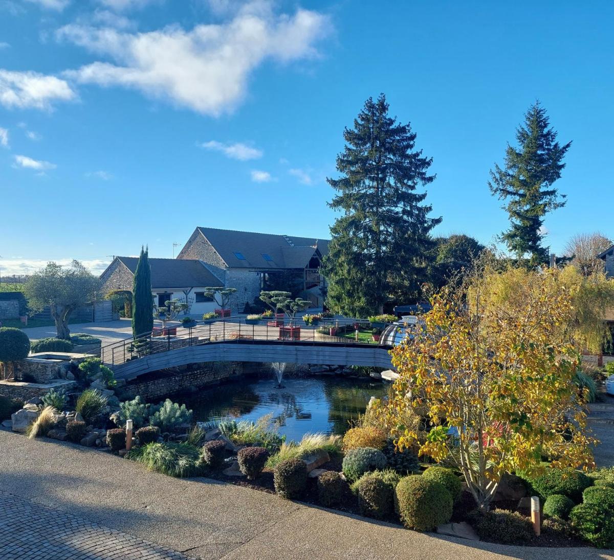 un pont sur un étang dans un jardin dans l'établissement Domaine de la Haie des Granges, à Ménilles
