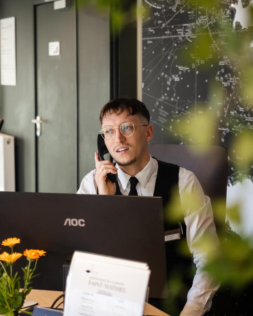un homme assis à une table parlant au téléphone portable dans l'établissement Hostellerie de la Pointe Saint-Mathieu - SPA & Restaurant, à Plougonvelin 103 autres photos