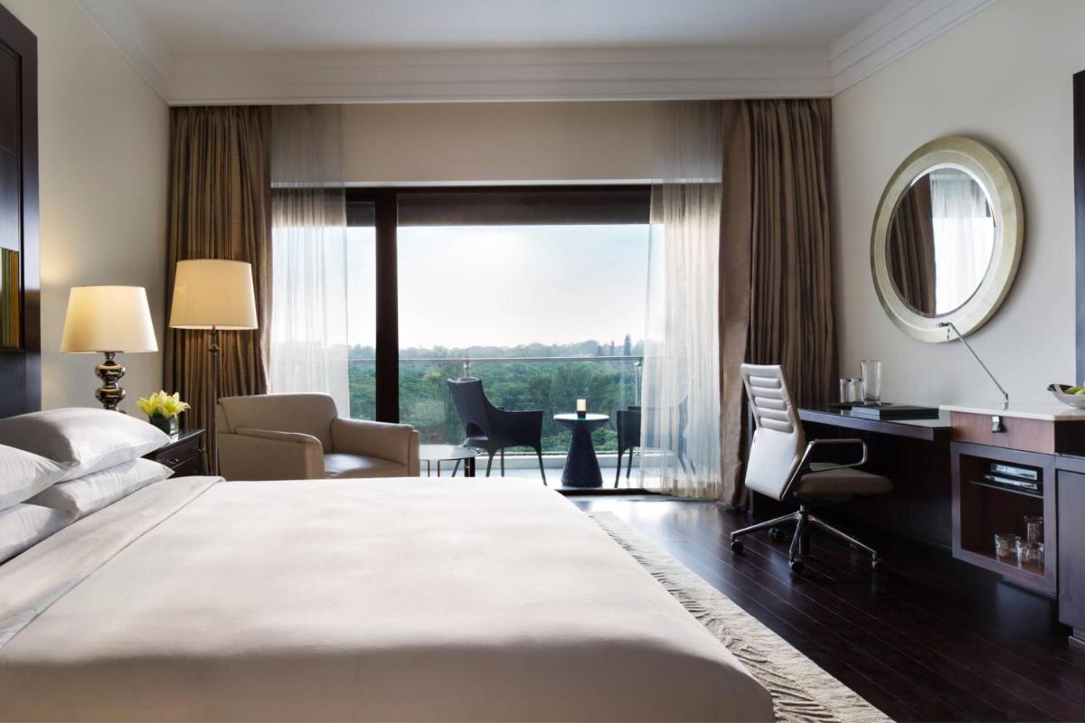 a bedroom with a large bed and a desk and chair at JW Marriott Hotel Bengaluru in Bengaluru