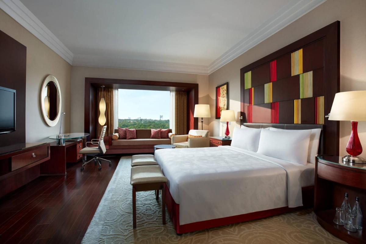 a bedroom with a large bed and a living room at JW Marriott Hotel Bengaluru in Bengaluru