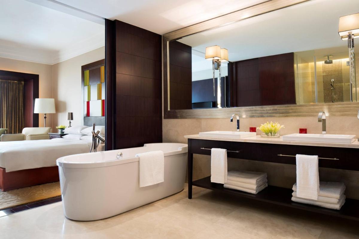 a bathroom with a tub and two sinks and a bed at JW Marriott Hotel Bengaluru in Bengaluru