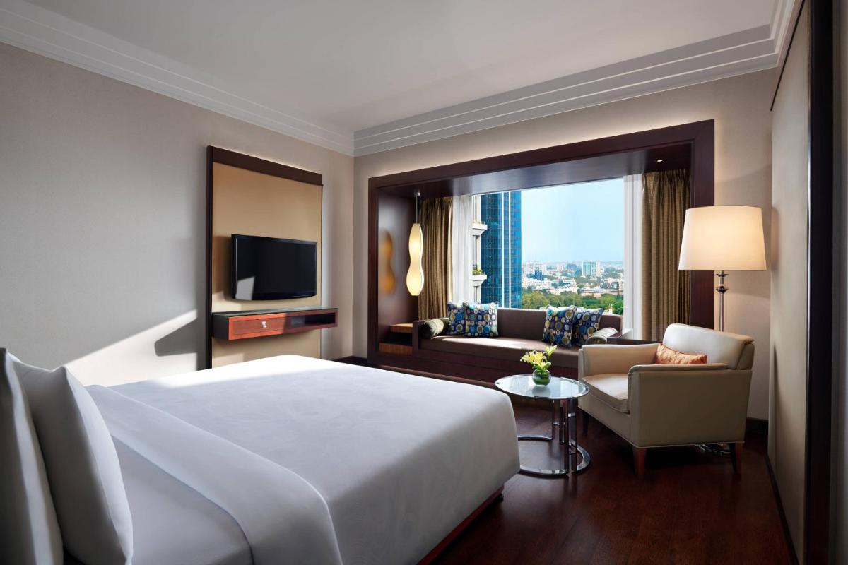a hotel room with a bed and a couch and a television at JW Marriott Hotel Bengaluru in Bengaluru a hotel room with a bed and a couch and a television at JW Marriott Hotel Bengaluru in Bengaluru