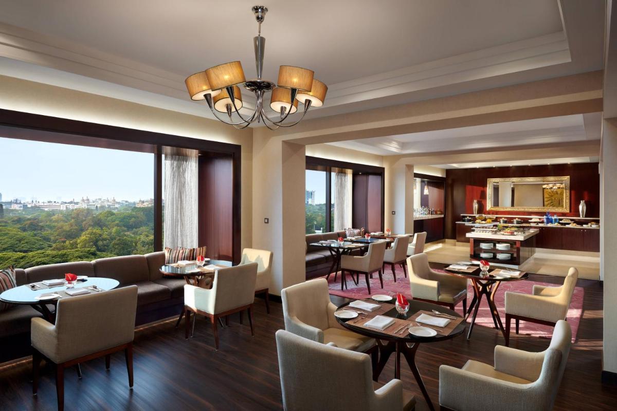 a restaurant with tables and chairs and a large window at JW Marriott Hotel Bengaluru in Bengaluru