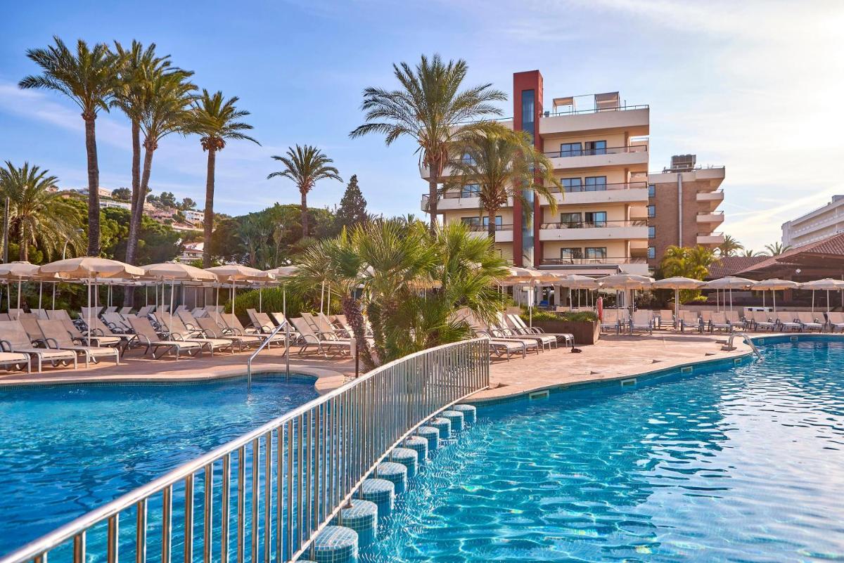 Una piscina con sillas y palmeras y un edificio. en Zafiro Rey Don Jaime, en Santa Ponsa