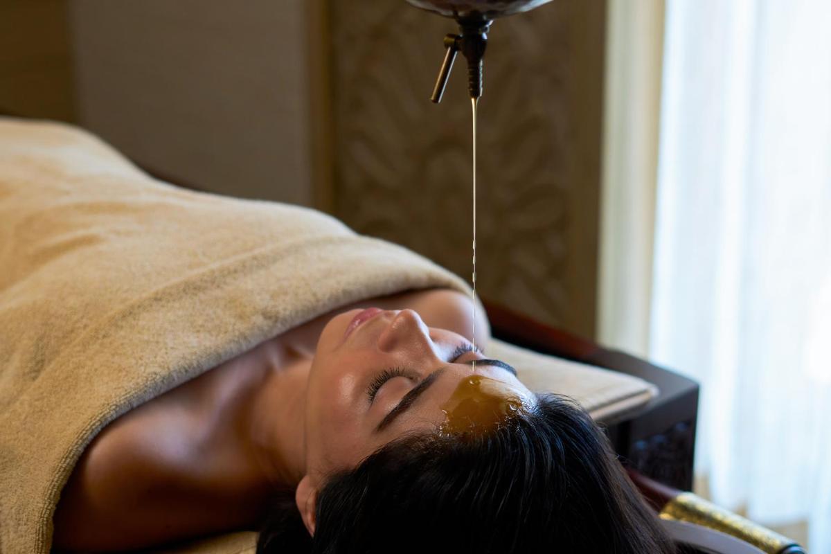 a woman is laying on a couch with a stream of oil at The Westin Resort & Spa Himalayas in Rishīkesh
