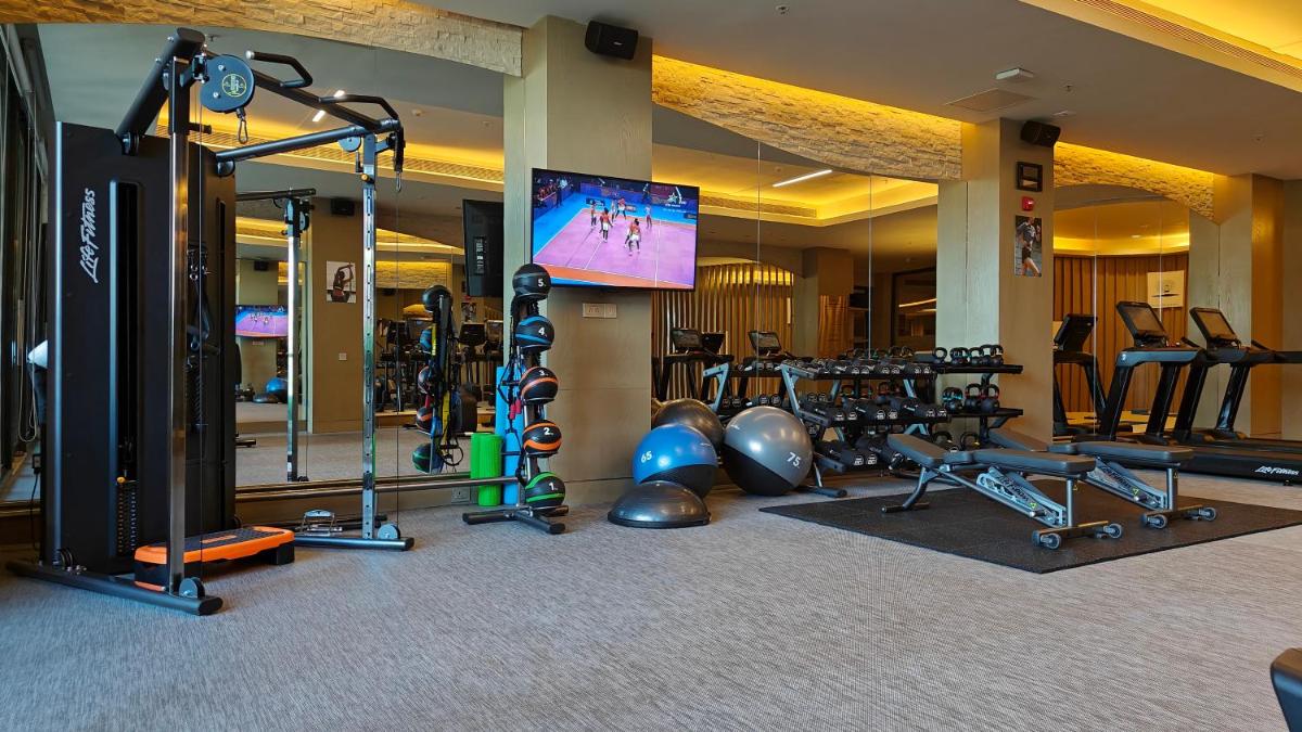 a gym with several tread machines and a flat screen tv at The Westin Resort & Spa Himalayas in Rishīkesh