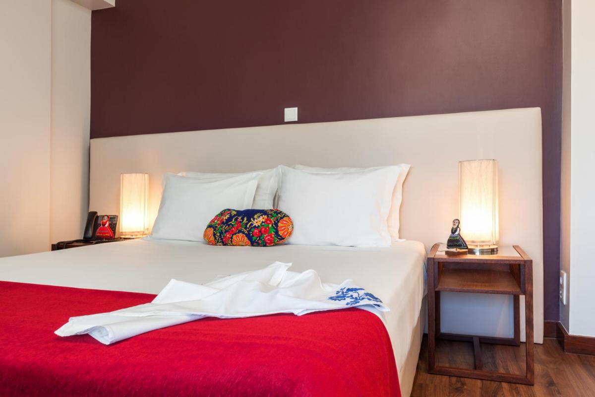 um quarto com uma cama branca e um cobertor vermelho em Hotel Rali Viana em Viana do Castelo