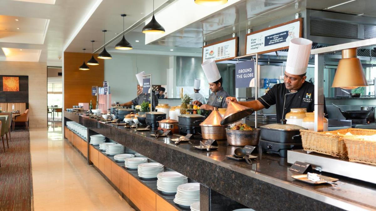 two chefs preparing food in a restaurant kitchen at Hyatt Place Pune Hinjawadi in Pune