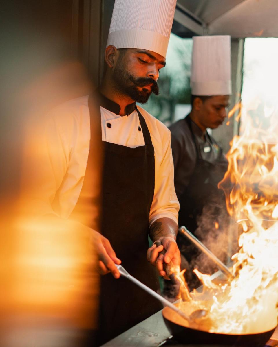 two chefs cooking in a wok in a kitchen at Hyatt Place Pune Hinjawadi in Pune
