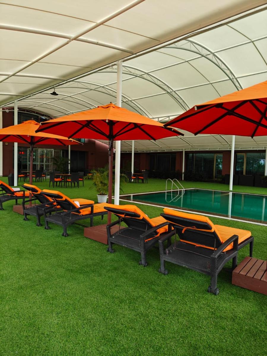 a row of tables and umbrellas in a building with a pool at Hyatt Place Pune Hinjawadi in Pune
