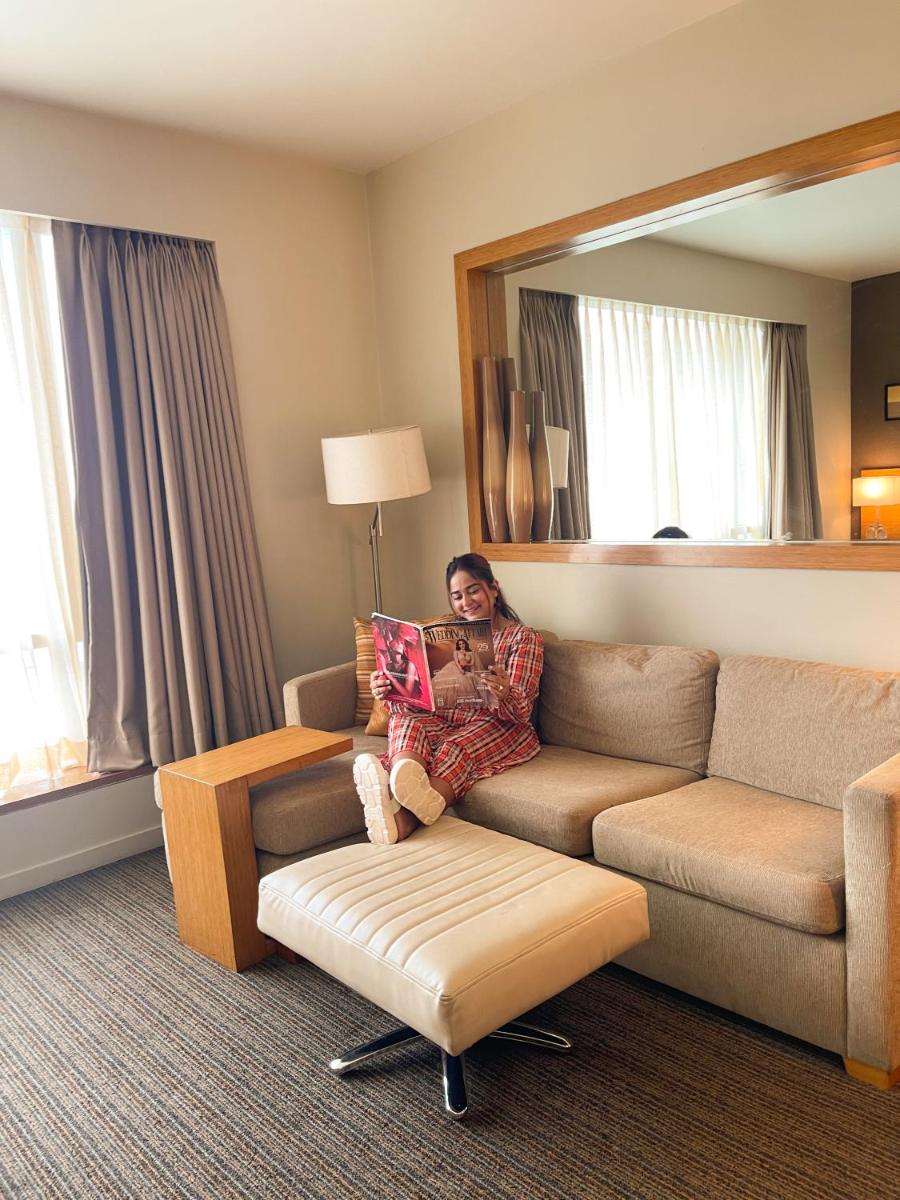 a woman sitting on a couch in a hotel room at Hyatt Place Pune Hinjawadi in Pune