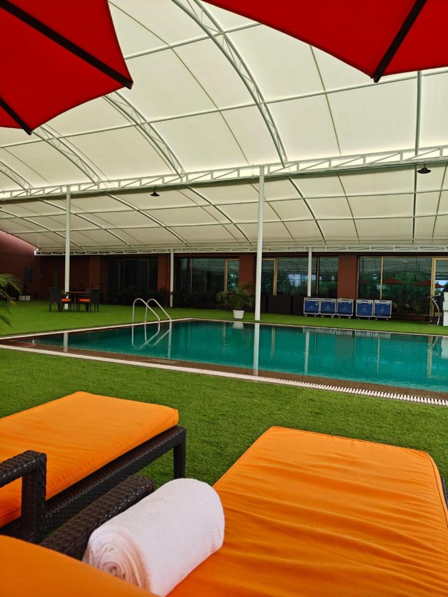 a swimming pool with two beds and an umbrella at Hyatt Place Pune Hinjawadi in Pune