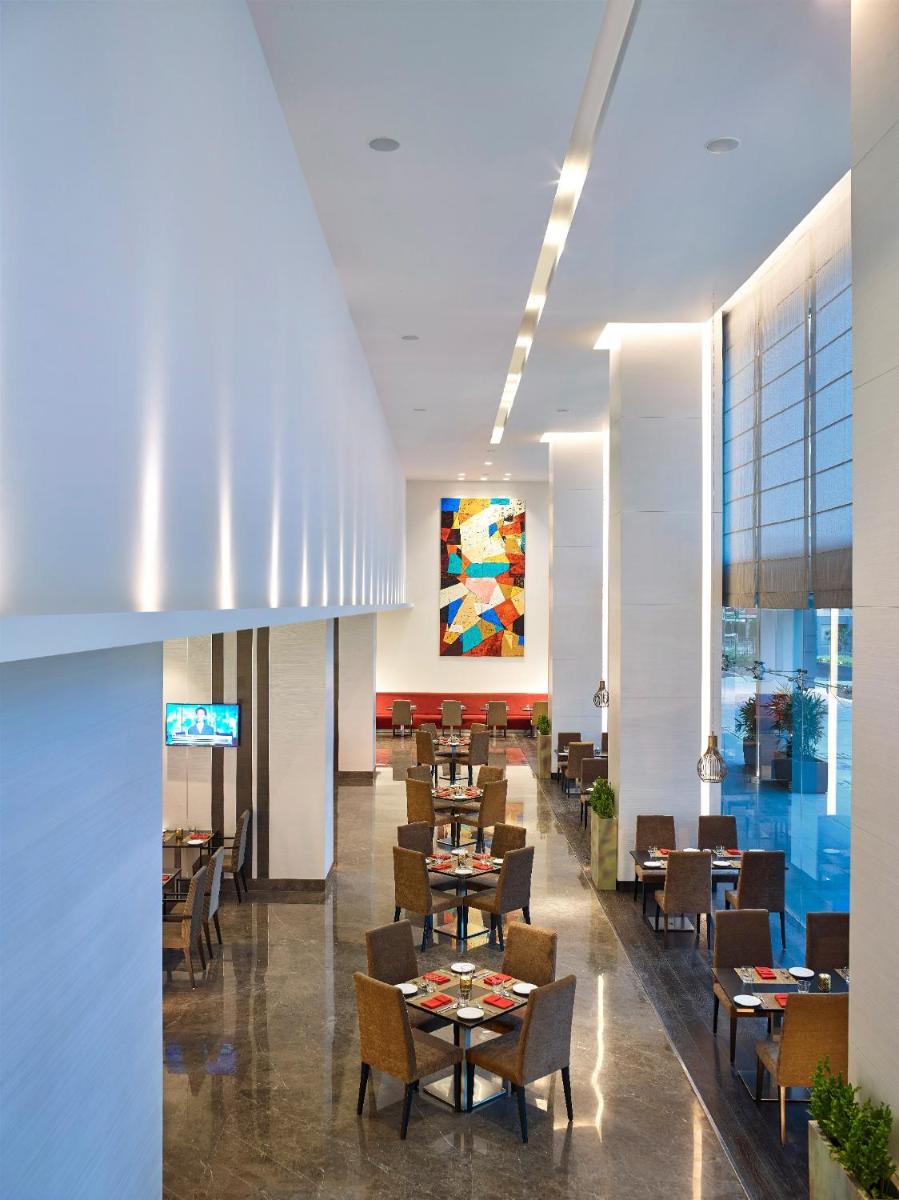 a dining room with tables and chairs and a restaurant at Vivanta Pune, Hinjawadi in Pune