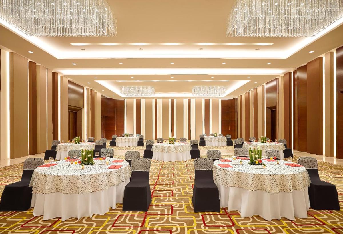 a banquet hall with tables and chairs and chandeliers at Vivanta Pune, Hinjawadi in Pune