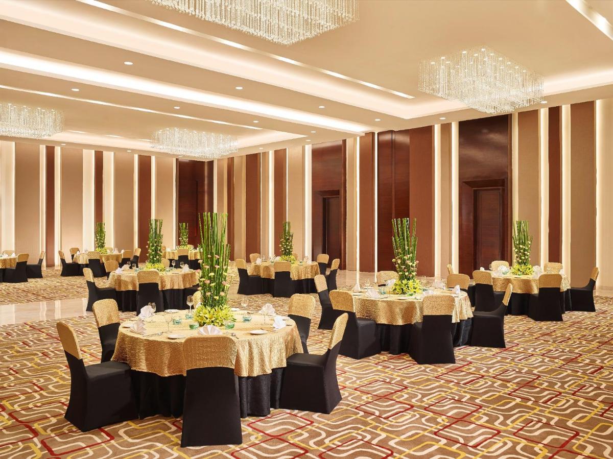 a banquet hall with tables and chairs and chandeliers at Vivanta Pune, Hinjawadi in Pune