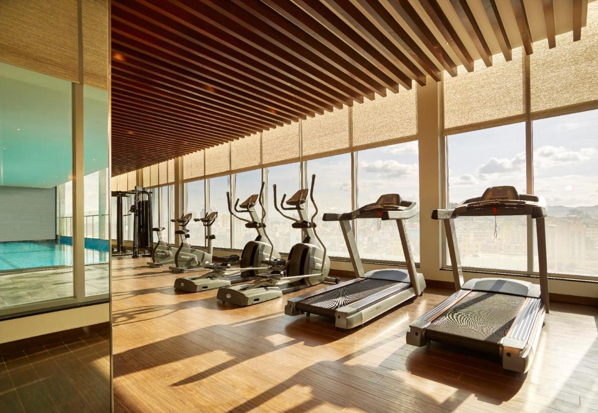 a gym with a row of treadmills and elliptical machines at Vivanta Pune, Hinjawadi in Pune