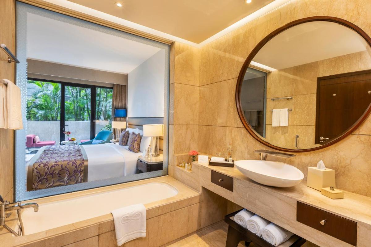 a bathroom with a tub and a large mirror at The Leela Ambience Convention Hotel Delhi in New Delhi
