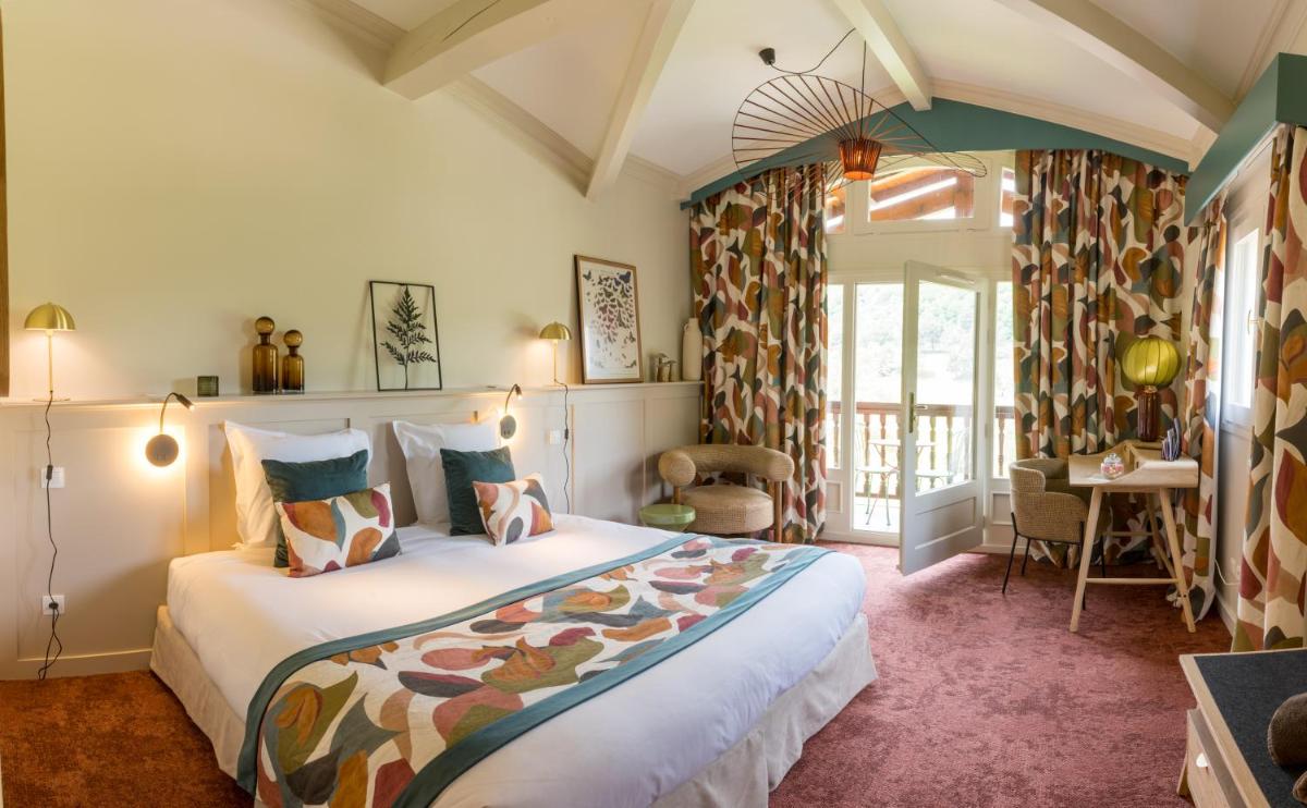 une chambre avec un grand lit dans une pièce dans l'établissement Le Domaine de Falgos Golf & Spa, à Saint-Laurent-de-Cerdans 49 autres photos