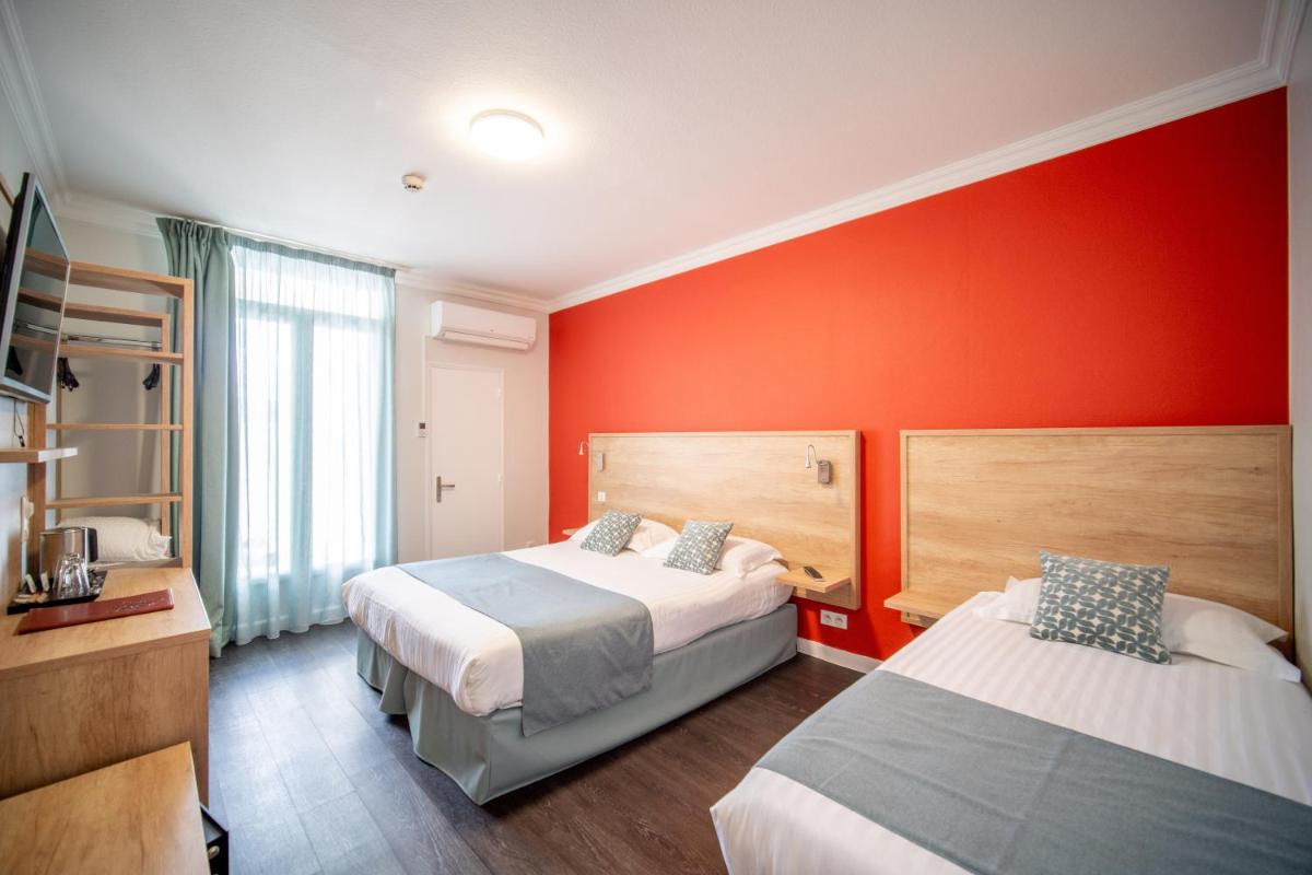 une chambre avec deux lits et un mur rouge dans l'établissement Logis - Hôtel Arc en Ciel et SPA Les Sables d'Olonne, à Les Sables-dʼOlonne