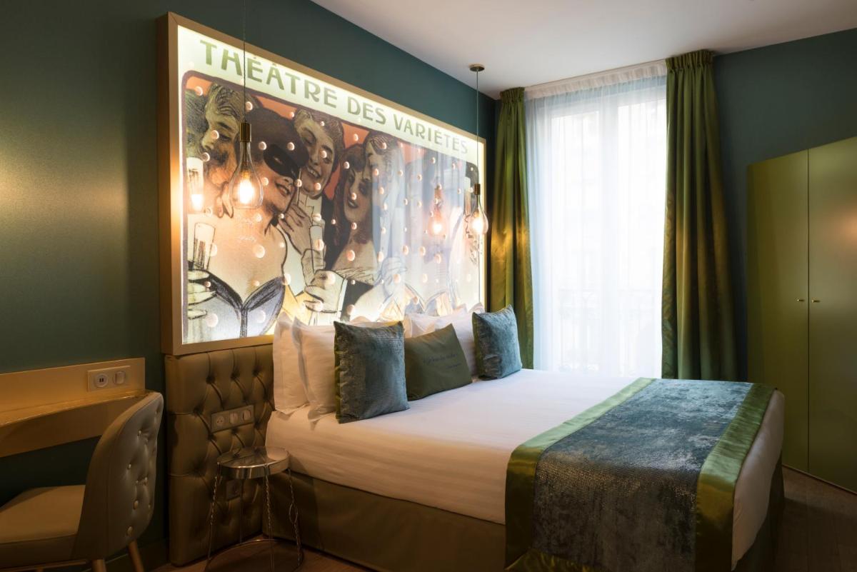 une chambre d'hôtel avec un lit à baldaquin sur le mur dans l'établissement Hotel Les Bulles De Paris, à Paris