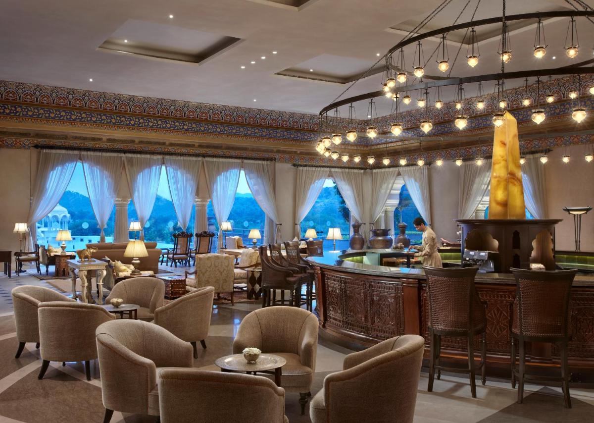 a hotel lobby with a bar and chairs at Fairmont Jaipur in Jaipur