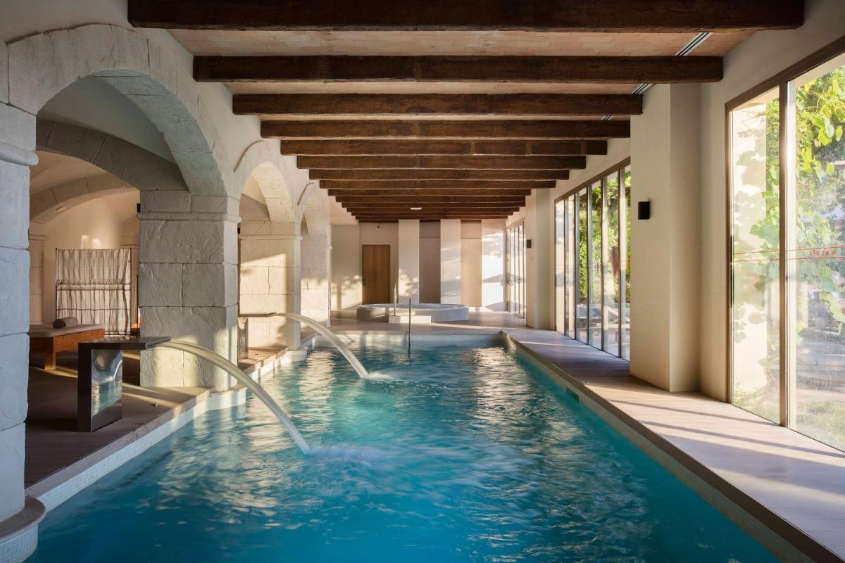 una piscina cubierta con cascadas en una casa en Hotel Peralada Wine Spa & Golf, en Peralada