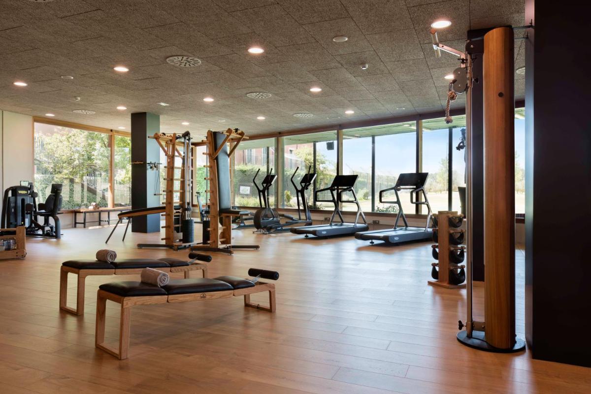 Un gimnasio con un montón de máquinas para correr y pilates. en Hotel Peralada Wine Spa & Golf, en Peralada