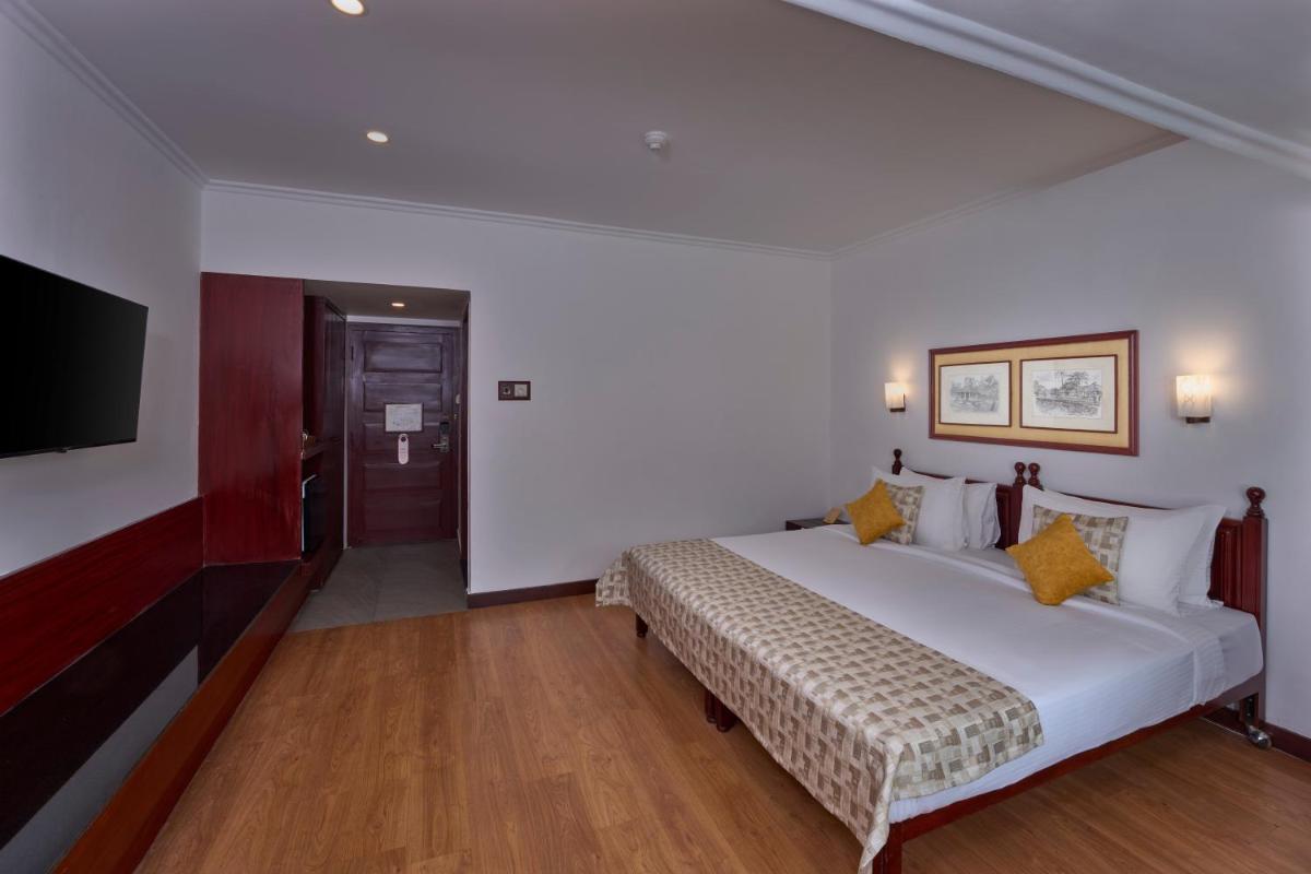 a bedroom with a large bed and a flat screen tv at Casino Hotel - CGH Earth, Cochin in Cochin