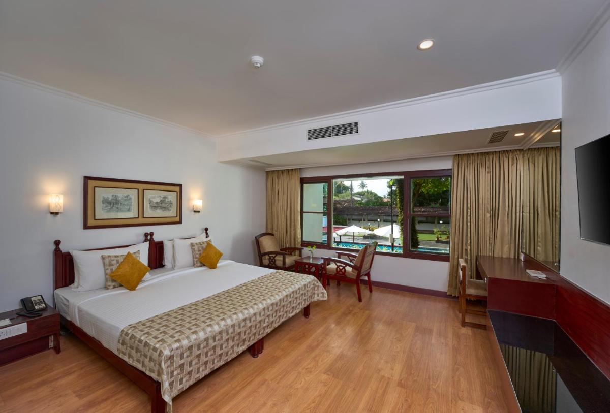 a hotel room with a large bed and a desk at Casino Hotel - CGH Earth, Cochin in Cochin