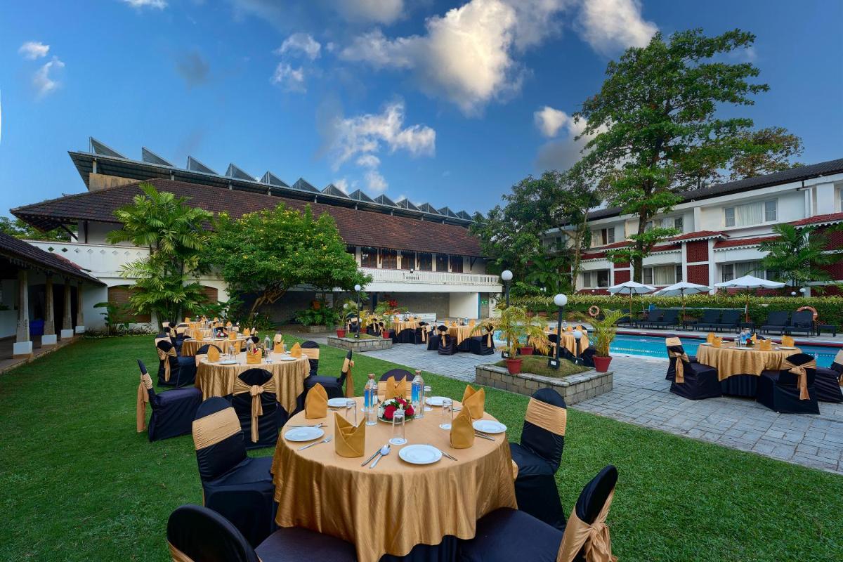 a restaurant with tables and chairs and a pool at Casino Hotel - CGH Earth, Cochin in Cochin