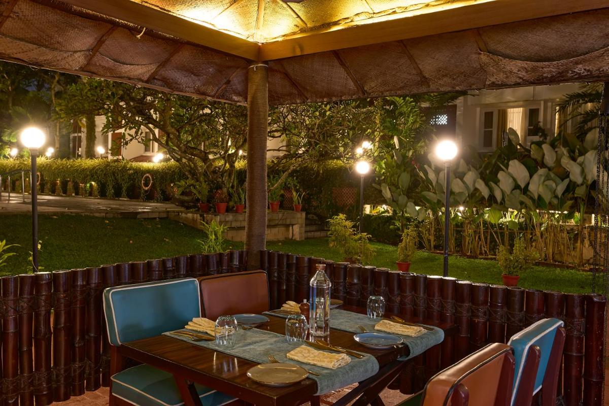a table and chairs under an umbrella at a restaurant at Casino Hotel - CGH Earth, Cochin in Cochin