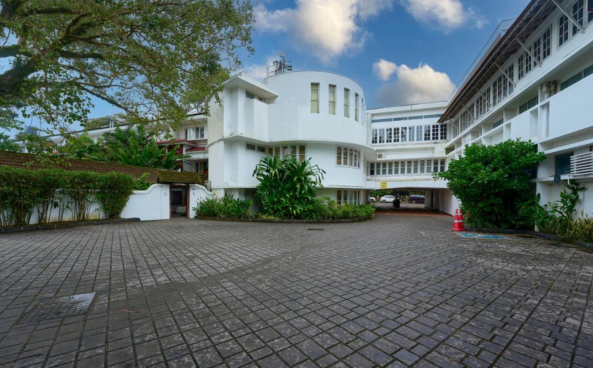 a large white building with a brick courtyard at Casino Hotel - CGH Earth, Cochin in Cochin