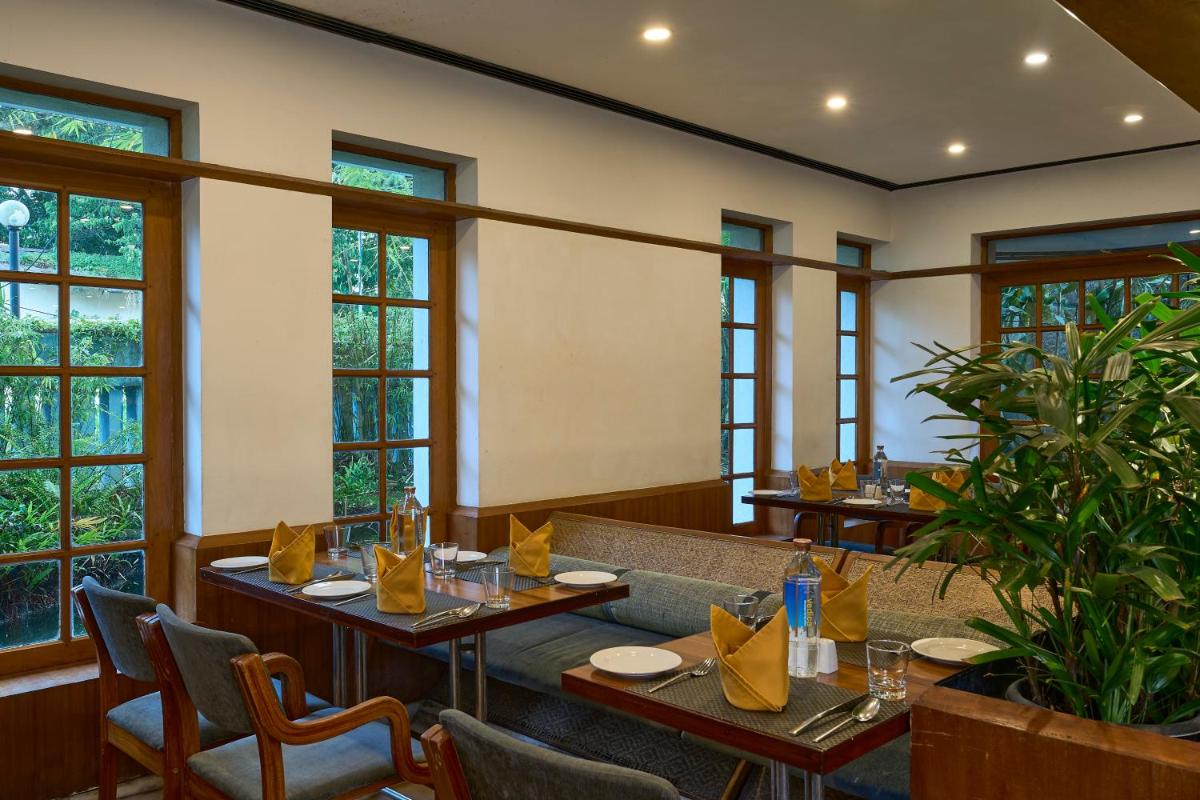 a restaurant with tables and chairs and windows at Casino Hotel - CGH Earth, Cochin in Cochin