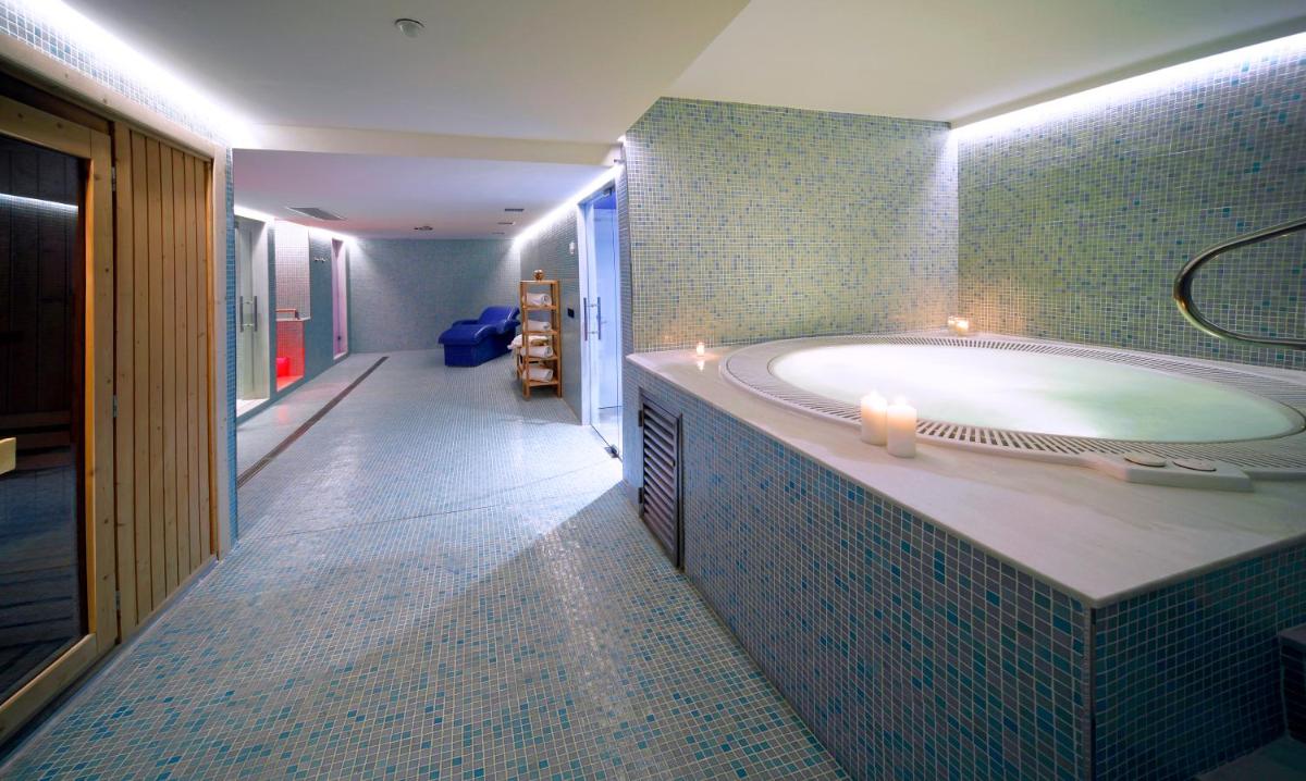 un baño grande con una bañera con velas. en Axor Barajas, en Madrid