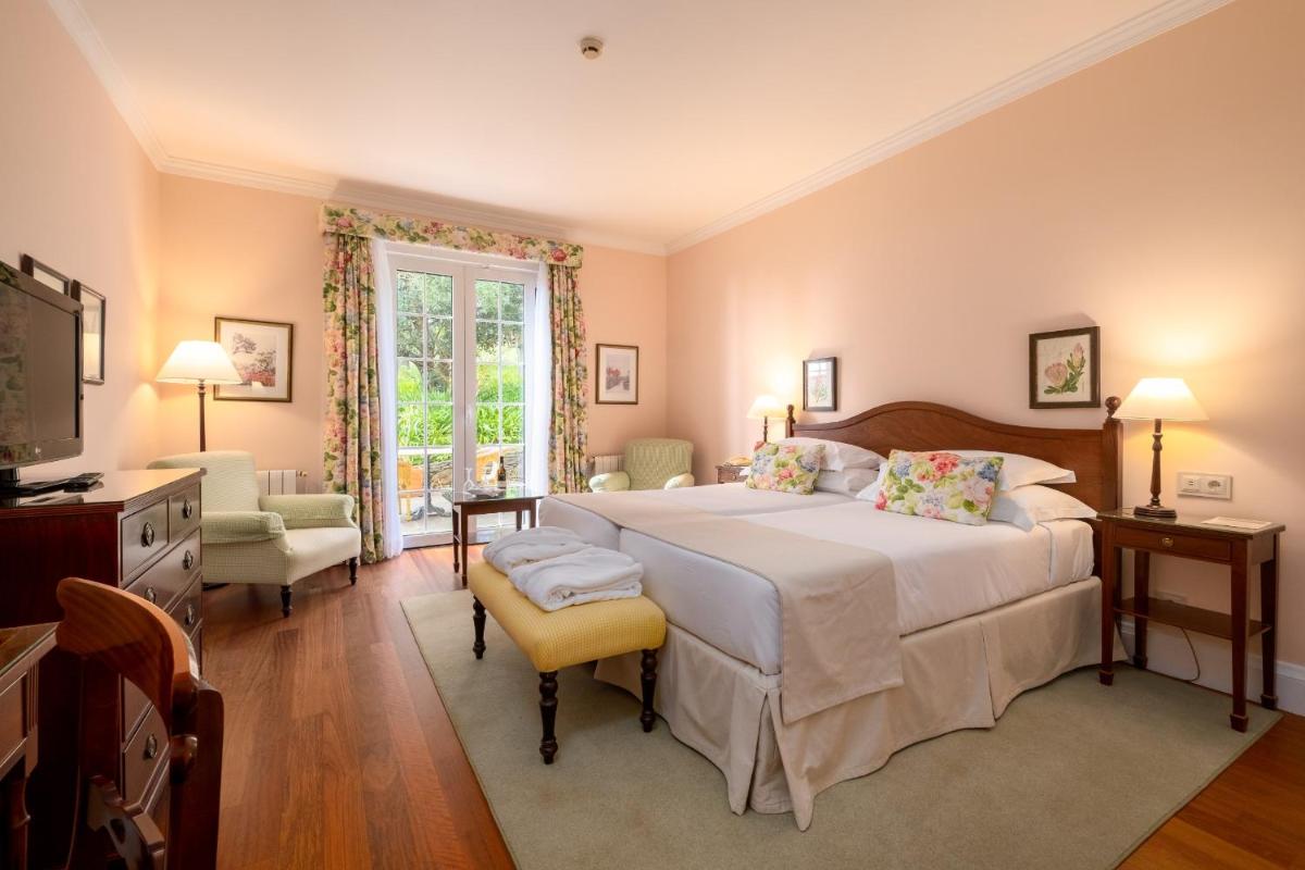 um quarto com uma cama grande e uma televisão em Casa Velha do Palheiro Relais & Chateaux no Funchal