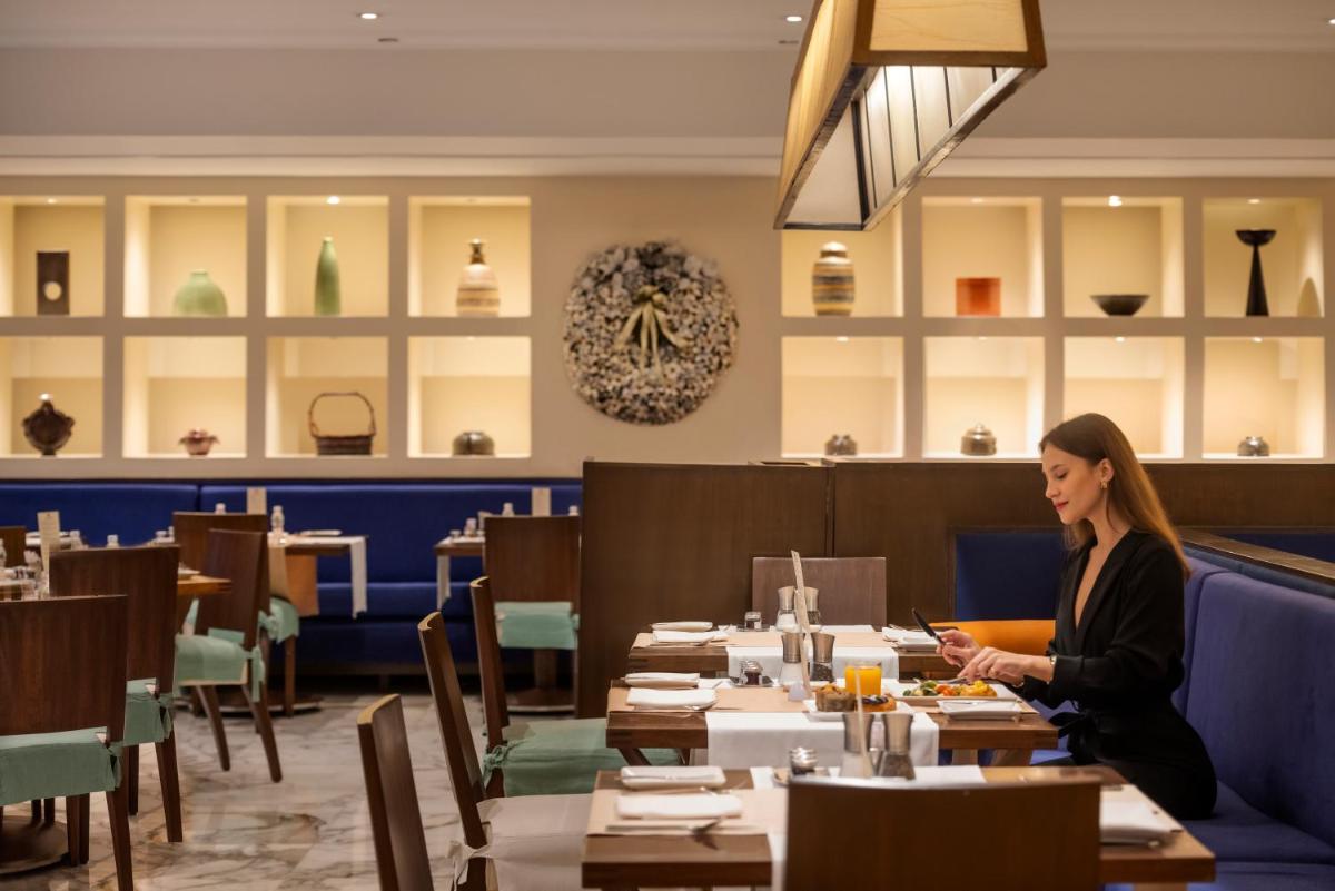 a woman sitting at a table in a restaurant at Trident Nariman Point in Mumbai a woman sitting at a table in a restaurant at Trident Nariman Point in Mumbai