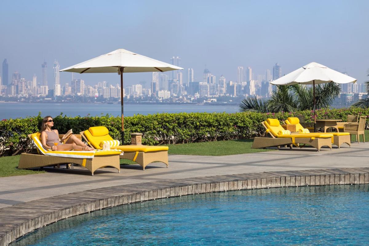 a woman sitting in yellow chairs next to a swimming pool at Trident Nariman Point in Mumbai a woman sitting in yellow chairs next to a swimming pool at Trident Nariman Point in Mumbai