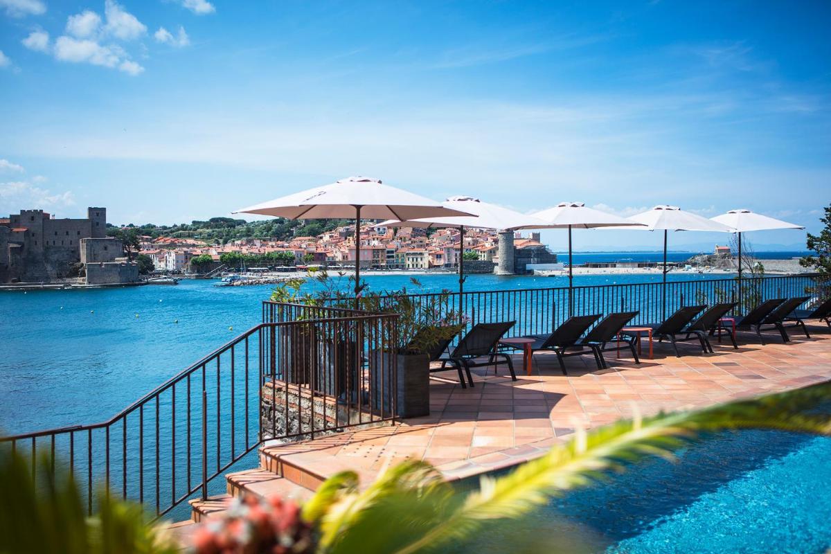 une terrasse avec des chaises et des parasols au bord de l'eau dans l'établissement Le Relais Des Trois Mas, à Collioure