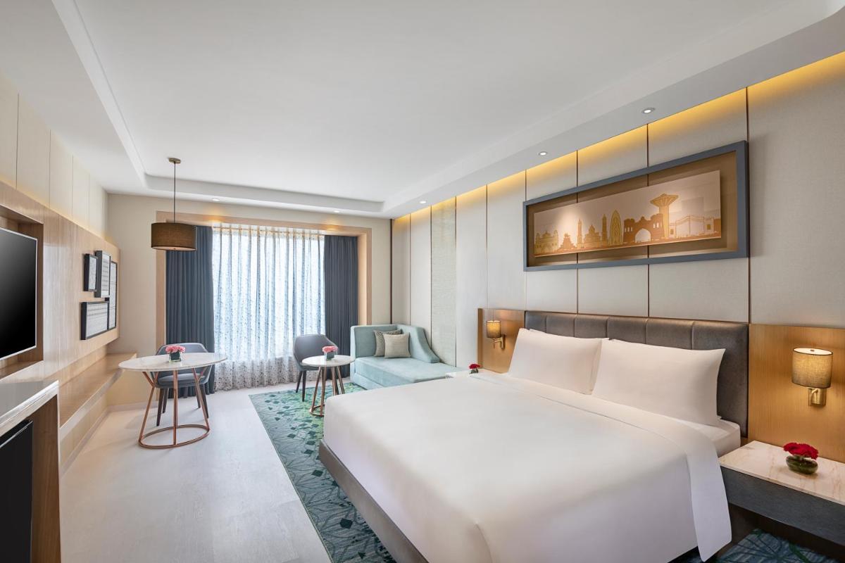 a hotel room with a large bed and a desk at Radisson Blu Hotel Amritsar in Amritsar