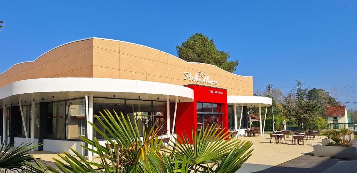 un bâtiment avec un bus rouge devant dans l'établissement Stella Maris, à Stella-Plage